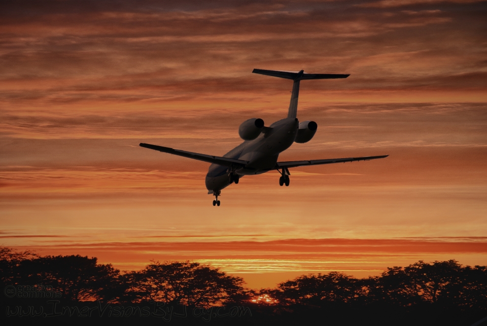 Airplane's descent against fiery sunset